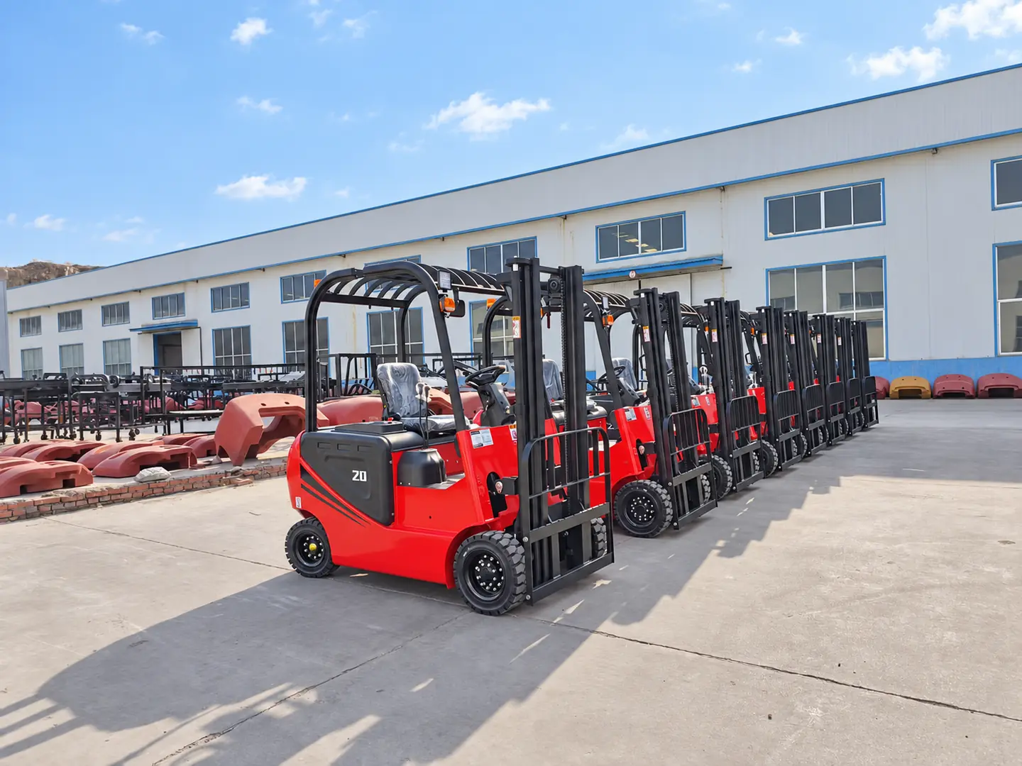 Red electric forklifts prepared in a row outside the workshop