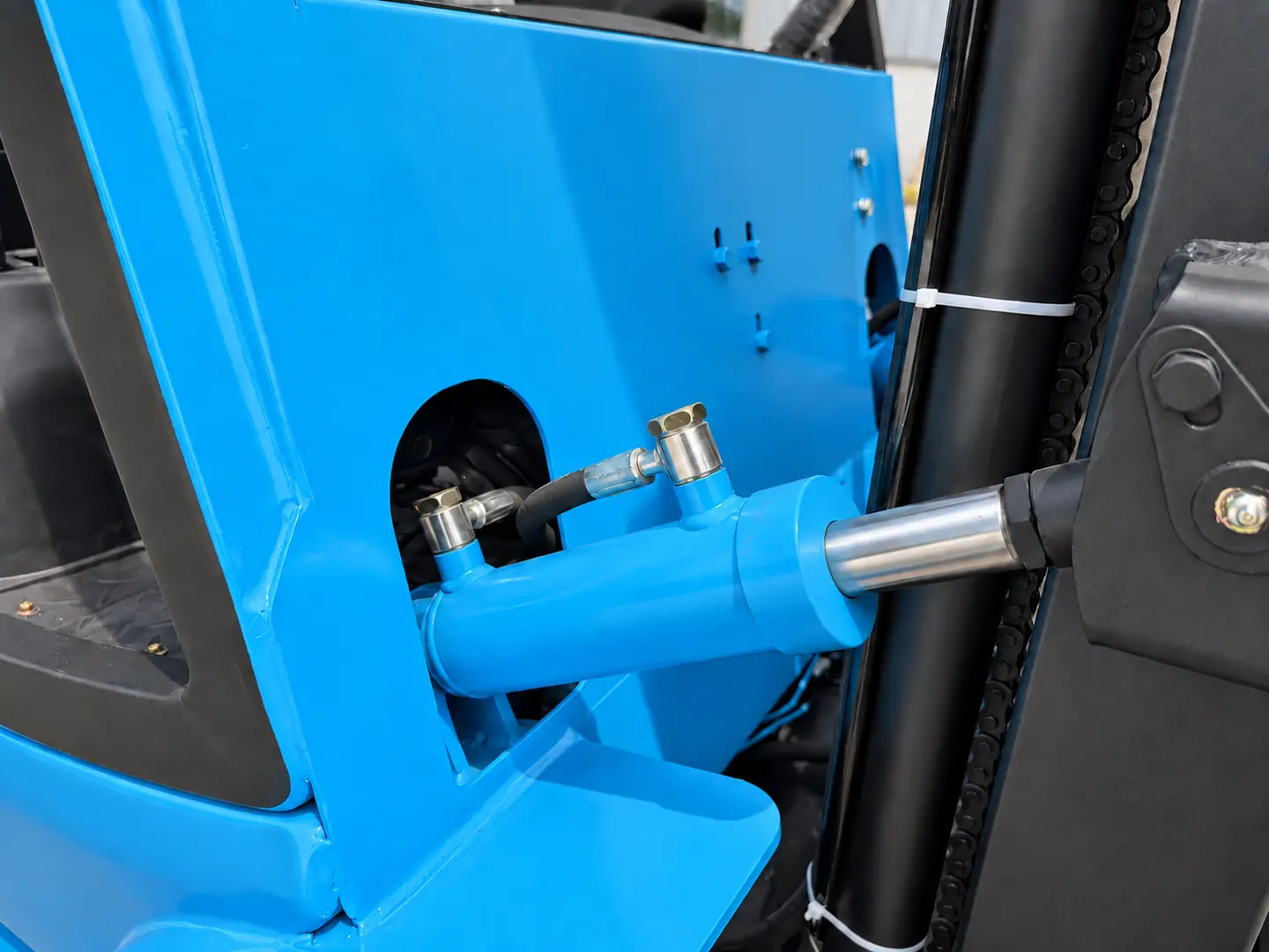 Mast tilt cylinder, hydraulic hose and linkage on a blue LETENG electric forklift